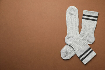 Pair of soft comfortable socks on brown background, top view. Space for text