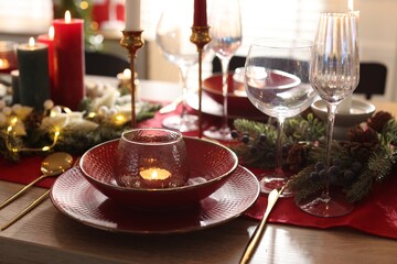 Christmas place setting with festive decor on wooden table in room, closeup