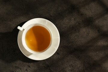 Refreshing green tea in cup on dark textured table, top view. Space for text