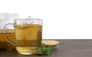 Aromatic mint tea in glass cup and fresh leaves on wooden table against white background, space for text