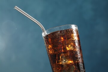 Refreshing iced cola on blue background, closeup