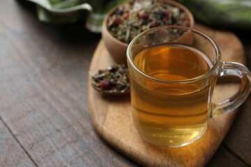 Delicious herbal tea and dry leaves on wooden table, closeup. Space for text