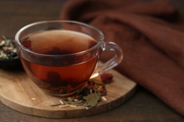 Delicious herbal tea and dry leaves on wooden table, closeup. Space for text