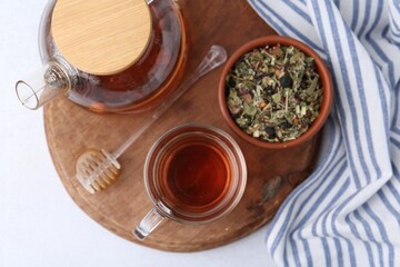 Delicious herbal tea, honey and dry leaves on white table, top view