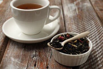 Aromatic tea and dried leaves on wooden table, closeup