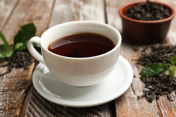 Aromatic tea, brew and fresh leaves on wooden table, closeup