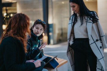 Three women are casually conversing outdoors, sharing ideas and appearing fully engaged in discussion.