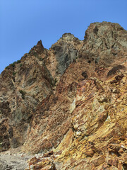 Majestic rocky cliff formation under a clear blue sky at a coastal location during daytime exploration