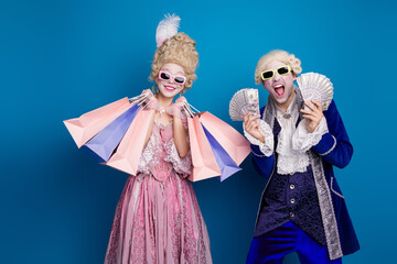 Cheerful couple in elegant vintage costumes showcases shopping bags and wealth, blending historical...