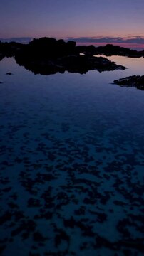 sunset over the sea, tide pools at blue hour, glowing in deep indigo and teal. Gentle ripples reflect twilight&rsquo;s fading light, evoking contemplation and quiet. Nature or poetic visuals.
