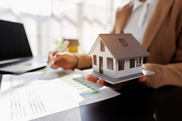 Female woman hand holding home model, investment small miniature white toy house. Mortgage property...