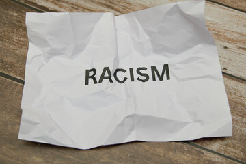 Crumpled paper with the word racism on wooden surface