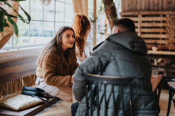 Two friends engaged in a lively conversation inside a warm and inviting cafe setting.