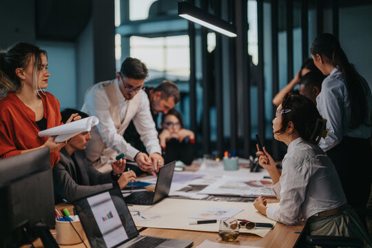 A multicultural team of people engaging in a brainstorming session. Colleagues are discussing ideas, analyzing proposals, and strategizing for business success in a contemporary office environment.