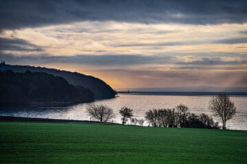 Idyllic Coastal View from Daugaard beach with Green Fields and a Tranquil Sunset Over Water, Denmark