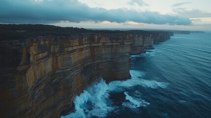 Dramatic coastal cliffs meet the turbulent ocean under a cloudy sky