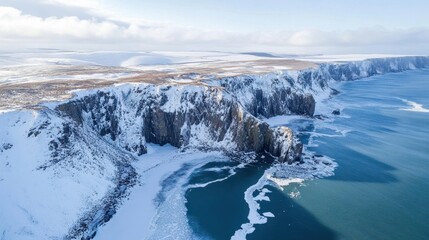 A breathtaking aerial shot of a snowy coastline, where frozen waves meet the rugged cliffs