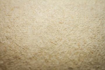 Extreme closeup of beige handmade paper with shallow depth of field.