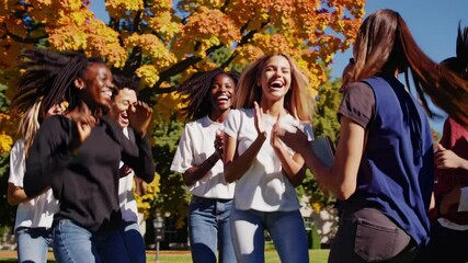 Diverse college students clapping, laughing, and sharing camaraderie during vibrant autumn day on sunlit campus, radiating joy and unity