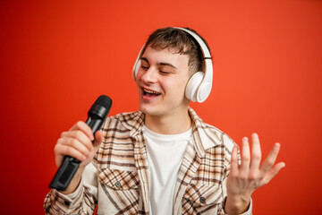 young man with headphones sing on microphone studio shot