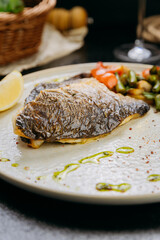 Grilled sea bream fillet with vegetables and lemon, plated with elegant garnish, fine dining style