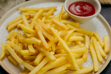 Crispy golden french fries with ketchup, served on a plate in a stylish restaurant setting