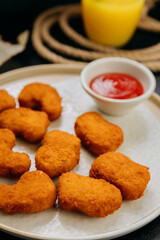 Crispy chicken nuggets with ketchup on plate with fresh ingredients in stylish food presentation