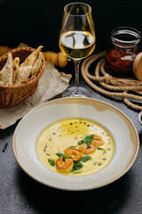 Creamy shrimp soup with spinach, garnished with chili flakes and herb oil, served in a gourmet style