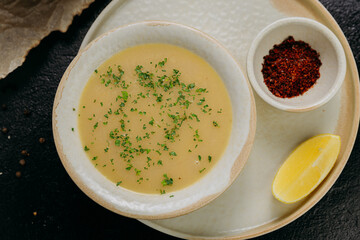 Creamy lentil soup with flatbread, sesame seeds, chili flakes, and lemon, served in an elegant style