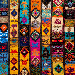  A colorful textile with various geometric patterns and designs, featuring vibrant colors such as red, blue, yellow, and green.