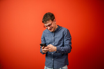 young man use mobile phone stand in front red background studio shot