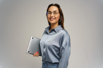 Woman smiling confidently while holding a laptop in a studio setting during a casual photoshoot
