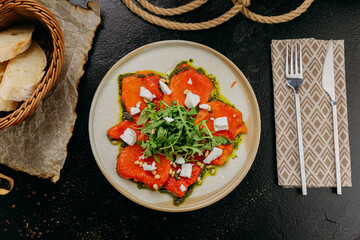 Roasted bell pepper carpaccio with arugula, feta cheese, pine nuts, and pesto, in gourmet style
