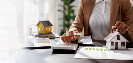 Business mortgage realtor with house model, sitting at desk, real estate agent manager working on...