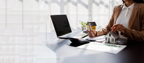 Business mortgage realtor with house model, sitting at desk, real estate agent manager working on...