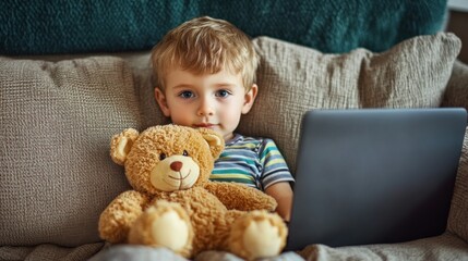cute toddler boy with teddy bear using laptop