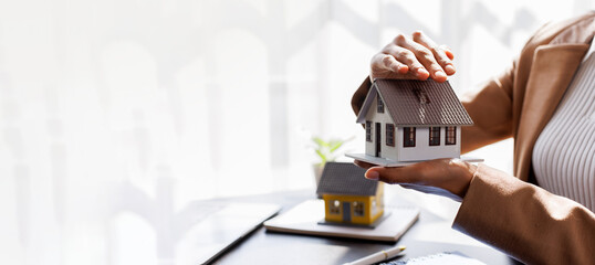Hand of woman holding model house, real estate mortgage insurance and mortgage loan property...