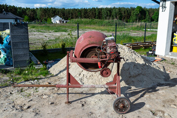 Mixing different ingredients for concrete in a portable concrete mixer.