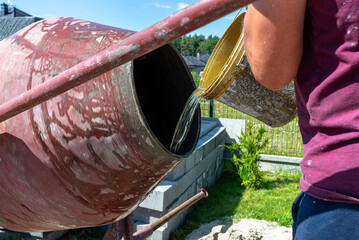 Mixing different ingredients for concrete in a portable concrete mixer.