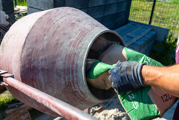 Mixing different ingredients for concrete in a portable concrete mixer.
