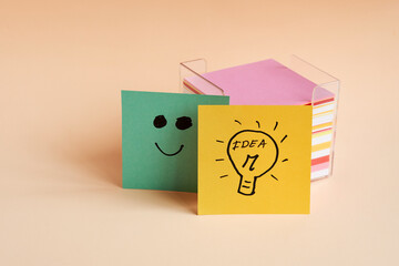 Creative notes with smiley face and light bulb idea on pastel background