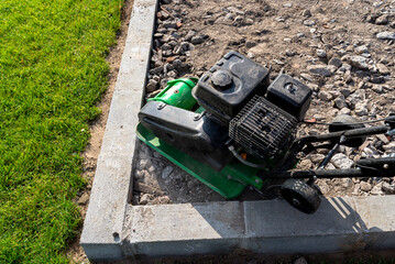 A man compacts rubble on a terrace under construction using a hand-held petrol-powered compactor.