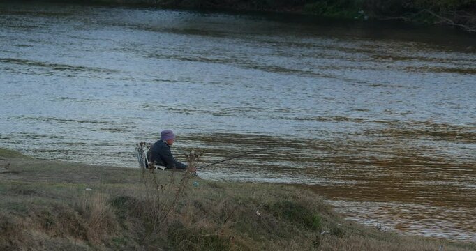 A Fisherman is Fishing on the River. He is Relaxing on a Chair 4K DCI Apple ProRes