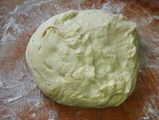 Fresh dough for baking. Kneaded dough on wooden surface. Food and baking theme.
