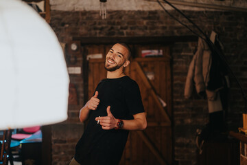 Young man expressing joy and positivity with thumb-up gesture in homely surroundings featuring soft lighting and rustic decor.