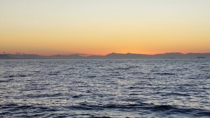 Hilly horizon line . Light yellow sky over the sea