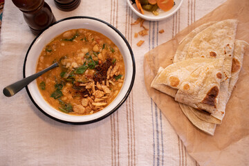 Vegan bean and spinach soup garnished with crispy onions and tamarind chutney