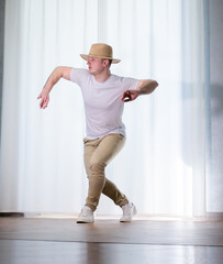 Young guy dancer in motion in a pose. A man performs a modern dance in casual clothes.