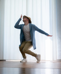Young guy dancer in motion in a pose. A man performs a modern dance in casual clothes.