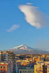 City, snowy volcano and cloud. Catania, Sicily, Italy